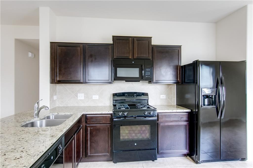 5916 Kennedy Street Austin, TX 78747 - Photo 2 of 25 Kitchen with black appliances, dark wood finish cabinetry, light stone counters, and backsplash