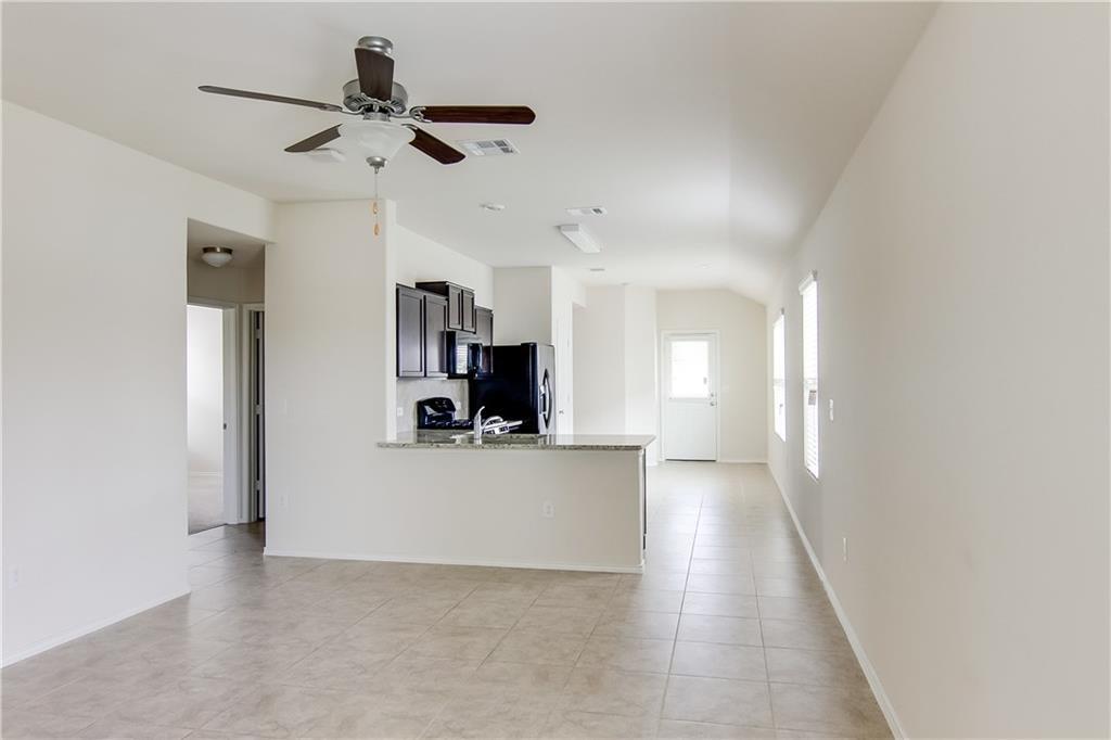 5916 Kennedy Street Austin, TX 78747 - Photo 5 of 25 Kitchen with a ceiling fan, light stone countertops, a peninsula, light tile patterned flooring, and black microwave