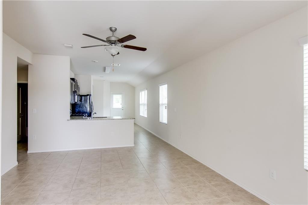 5916 Kennedy Street Austin, TX 78747 - Photo 6 of 25 Unfurnished living room featuring a ceiling fan, vaulted ceiling, and light tile patterned floors