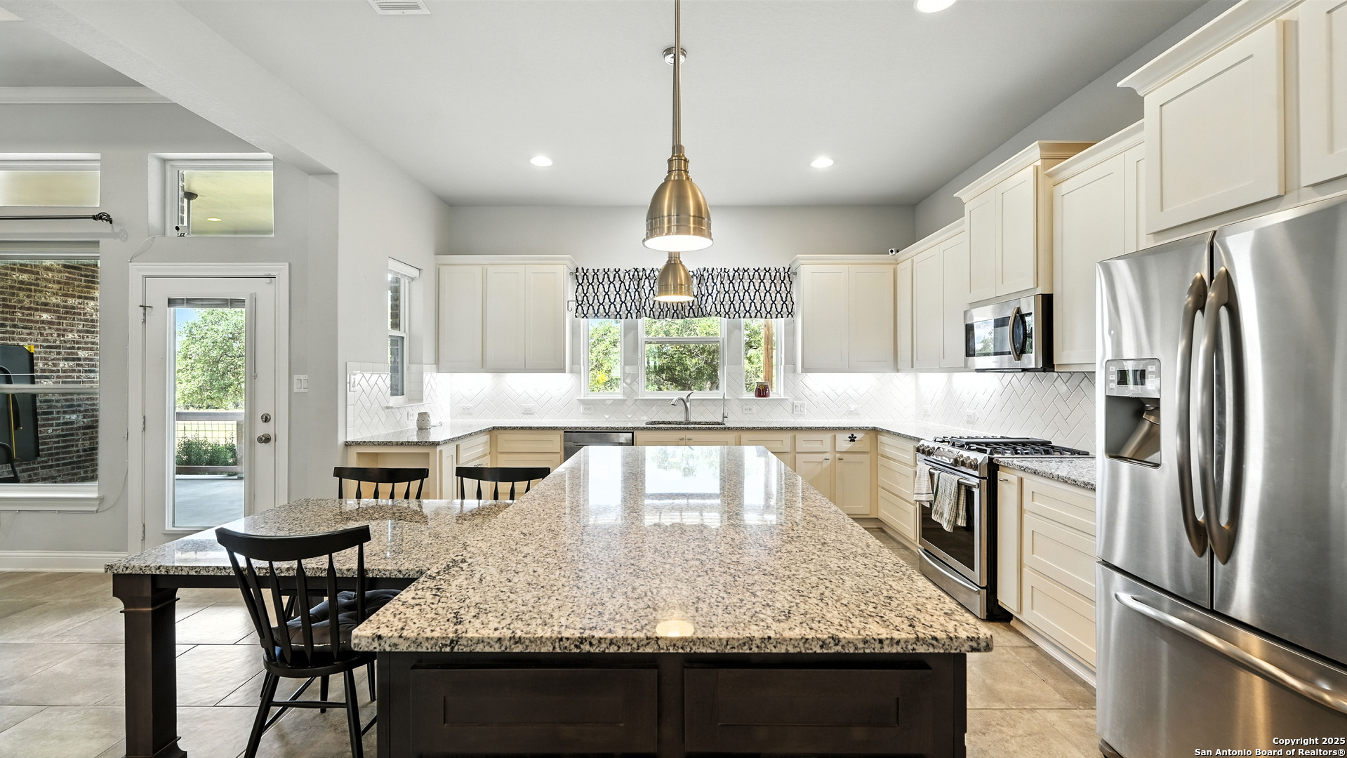 179 Prairie Dawn Spring Branch, TX 78070 - Photo 4 of 45 a kitchen with kitchen island granite countertop a table chairs stove and refrigerator