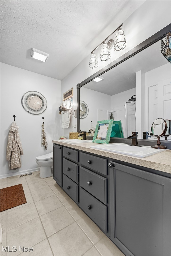 4038 Gardiner Run Akron, OH 44321 - Photo 23 of 38 Full bathroom featuring double vanity, light tile patterned floors, and a textured ceiling