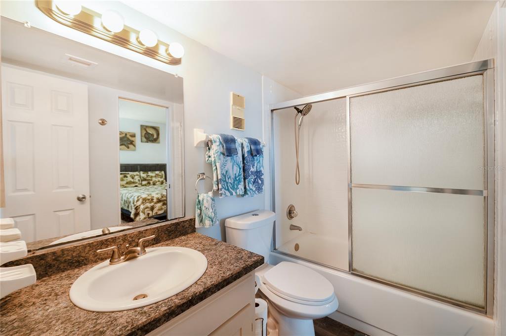 4453 South Atlantic Avenue, Unit 604 Ponce Inlet, FL 32127 - Photo 20 of 28 a bathroom with a granite countertop sink toilet a mirror and shower