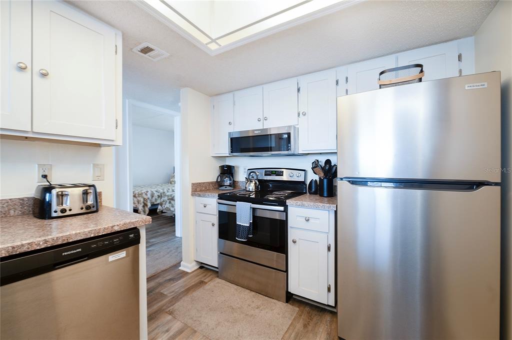 4453 South Atlantic Avenue, Unit 604 Ponce Inlet, FL 32127 - Photo 6 of 28 a kitchen with stainless steel appliances granite countertop a refrigerator a stove a sink and a granite counter tops with white cabinets