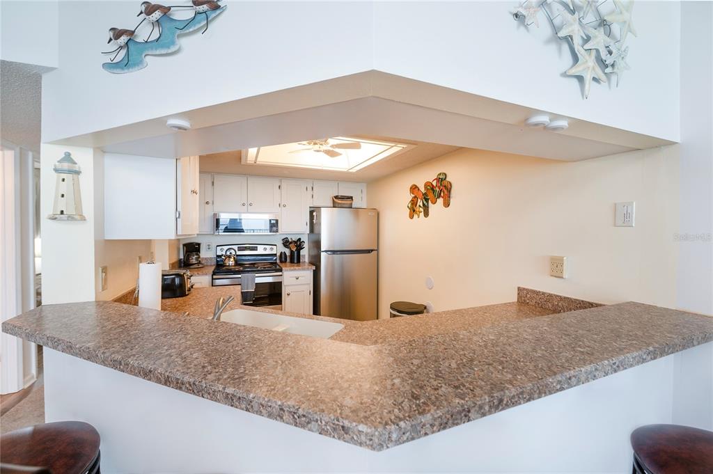 4453 South Atlantic Avenue, Unit 604 Ponce Inlet, FL 32127 - Photo 7 of 28 a kitchen with stainless steel appliances granite countertop a sink refrigerator and cabinets