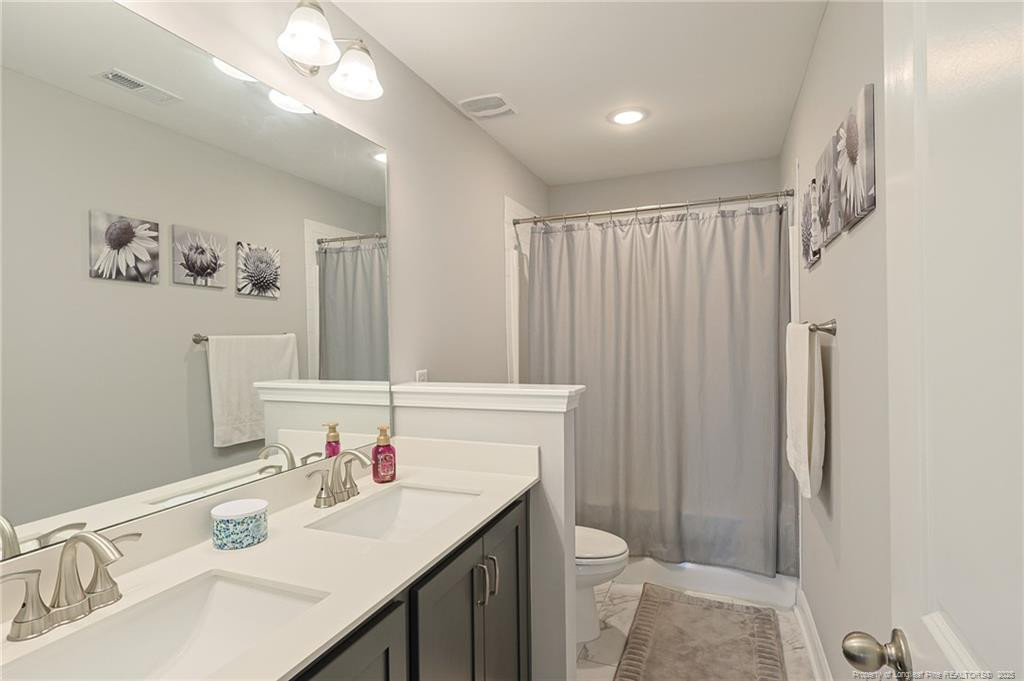 7810 Rufus Johnson Road St. Pauls, NC 28384 - Photo 14 of 24 a bathroom with a sink vanity mirror and toilet