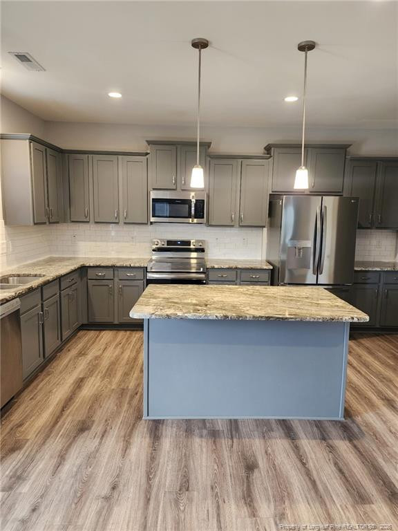 7810 Rufus Johnson Road St. Pauls, NC 28384 - Photo 8 of 27 a large kitchen with kitchen island a sink wooden floor and stainless steel appliances