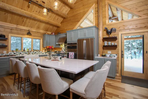 a dining room with stainless steel appliances granite countertop a dining table chairs and a refrigerator