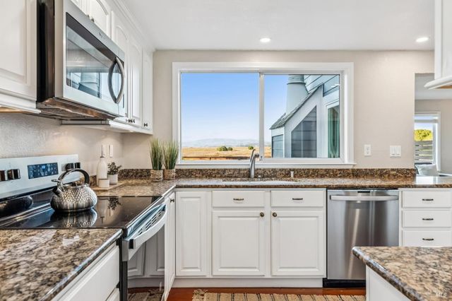 a dining room with furniture a kitchen view and wooden floor