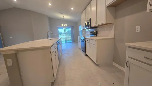 a large kitchen with a large counter top a sink stainless steel appliances and cabinets