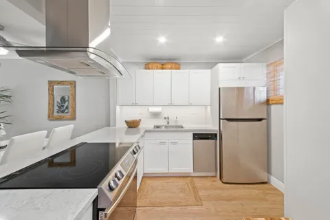 a kitchen with stainless steel appliances granite countertop a refrigerator a stove and a sink