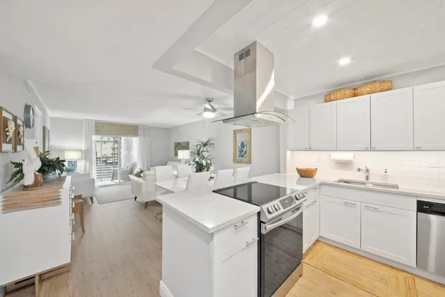 a kitchen with a sink dishwasher stove and white cabinets with wooden floor