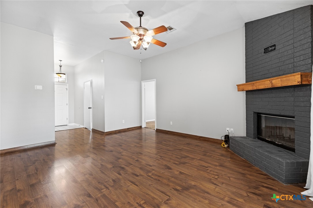 808 Silver Stone Drive Temple, TX 76502 - Photo 6 of 31 an empty room with wooden floor a ceiling fan and a fireplace