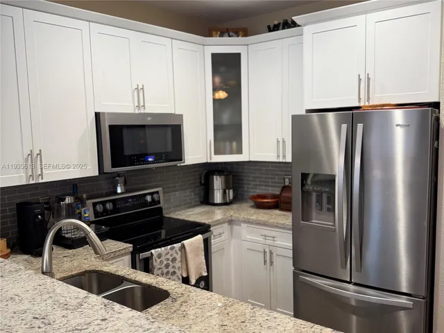 a kitchen with a refrigerator sink and white cabinets