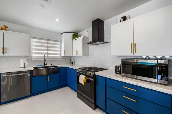 a kitchen with stainless steel appliances granite countertop a stove a sink and a microwave