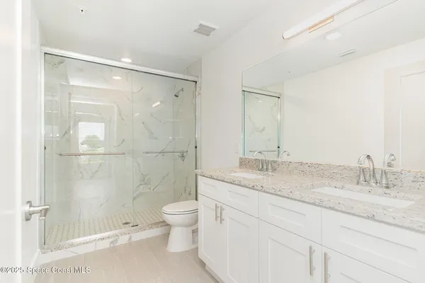 a bathroom with a granite countertop sink a toilet and shower