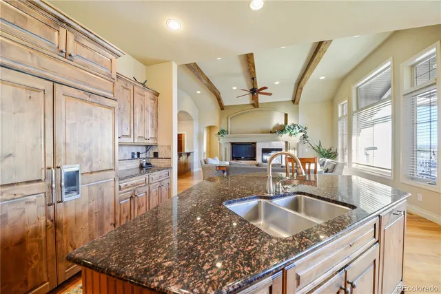 a kitchen with stainless steel appliances granite countertop a sink a counter space and living room view