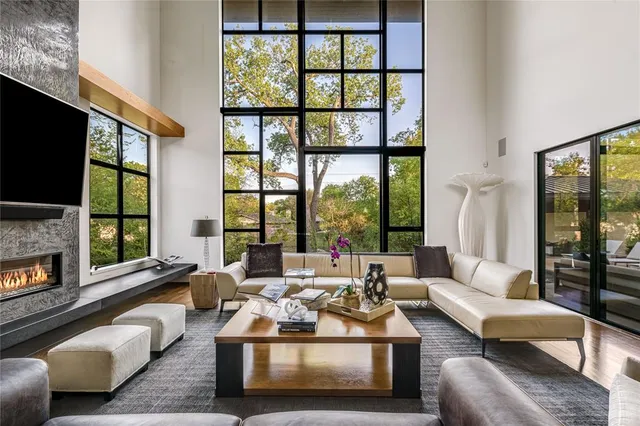 a living room with furniture large windows and fireplace