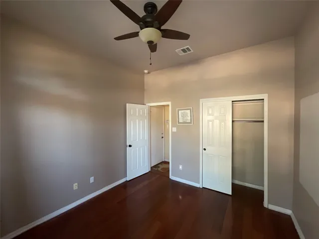 an empty room with closet and a chandelier fan