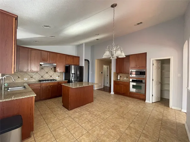 a kitchen with stainless steel appliances a stove a refrigerator a sink a oven with a dining table and chairs