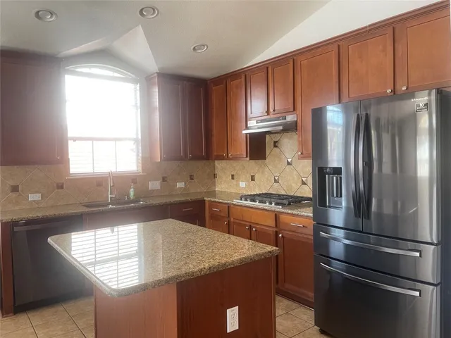 a kitchen with kitchen island granite countertop a sink appliances cabinets and counter space