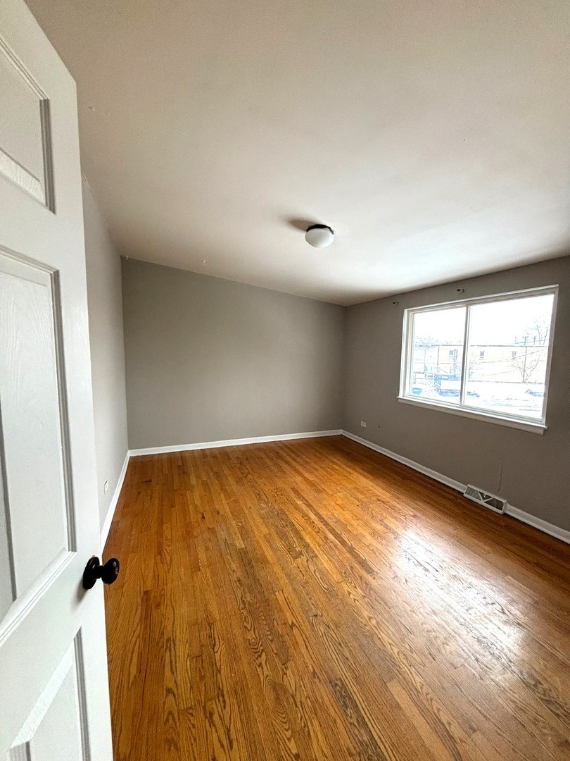 66 East Blecke Avenue, Unit 66 Addison, IL 60101 - Photo 10 of 14 an empty room with wooden floor and windows