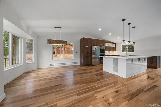 a large kitchen with stainless steel appliances kitchen island a large counter top and wooden floors