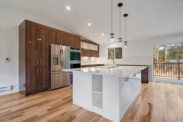 a large kitchen with stainless steel appliances a large counter top a refrigerator a stove a sink and a wooden floors