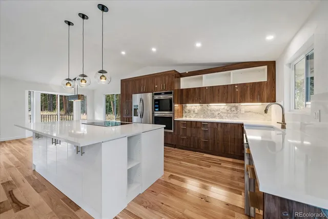 a large kitchen with kitchen island a large counter top stainless steel appliances and cabinets