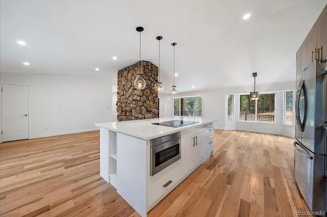 a large kitchen with granite countertop a stove and a wooden floors