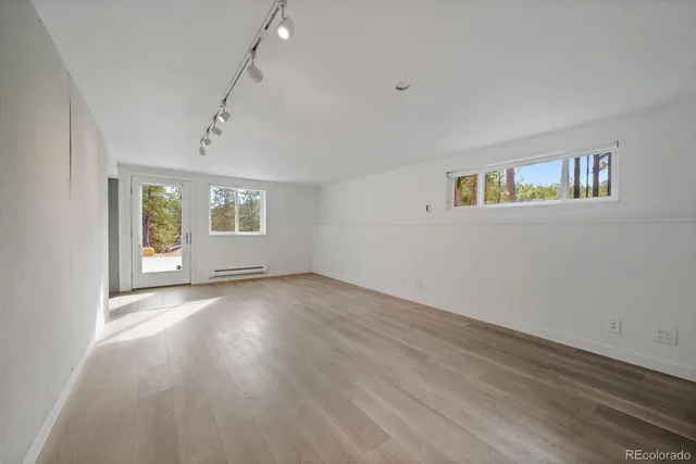 a view of an empty room with a window and wooden floor