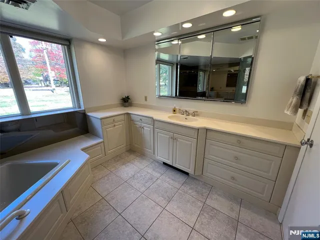 a large bathroom with a large tub sink and mirror