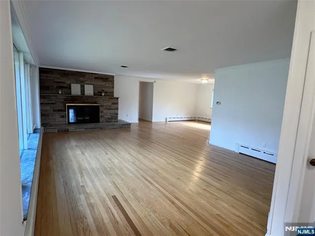 an empty room with wooden floor fireplace and windows