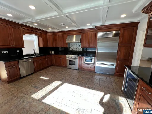 a large kitchen with a large counter top space a sink and stainless steel appliances