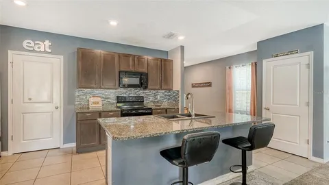 a kitchen with kitchen island granite countertop a sink cabinets and refrigerator