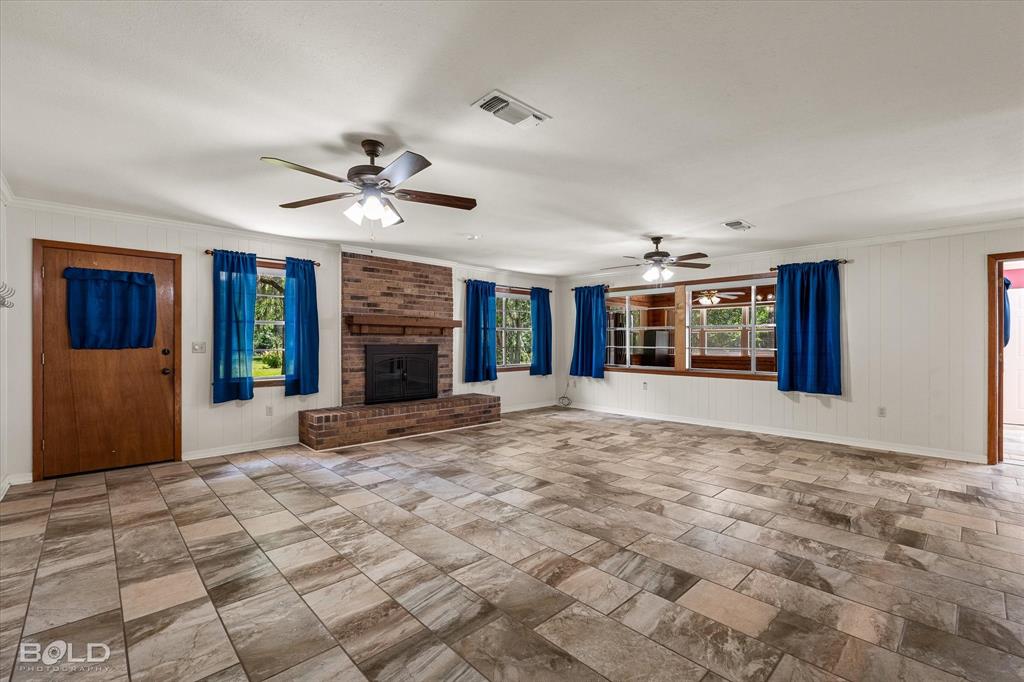 225 Marie Road Ringgold, LA 71068 - Photo 20 of 40 Spacious room featuring large format tile flooring, a brick fireplace with hearth, multiple windows, and two ceiling fans
