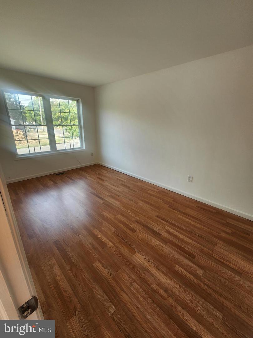 281 Spruce Street Bridgeton, NJ 08302 - Photo 10 of 18 an empty room with wooden floor and windows