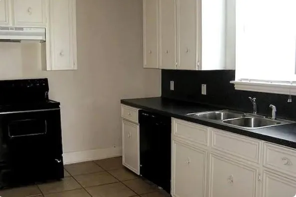 a kitchen with granite countertop white cabinets and black appliances