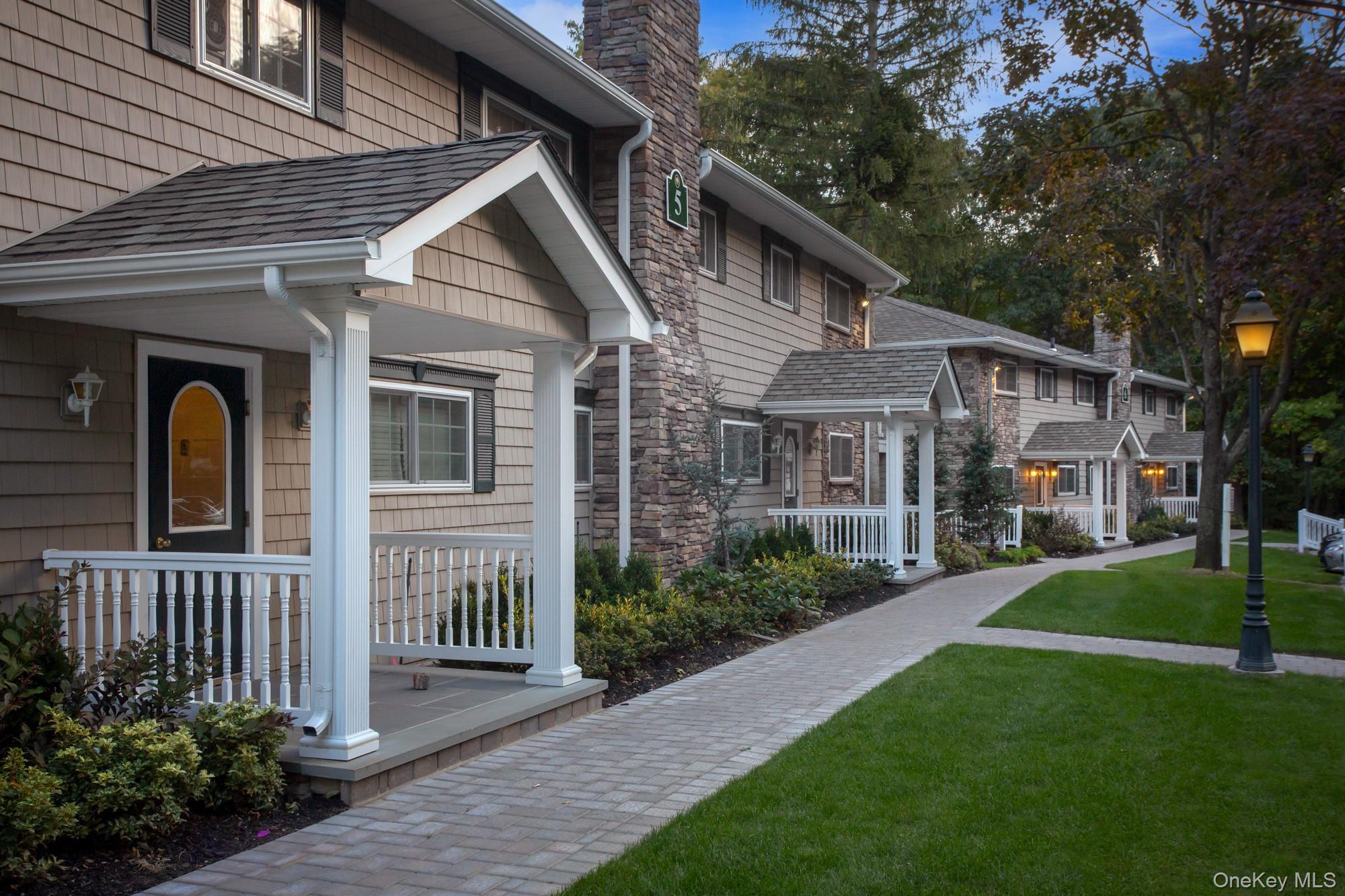 a front view of a house with a garden and trees