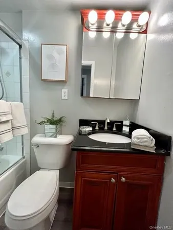 a bathroom with a granite countertop sink a toilet and a mirror