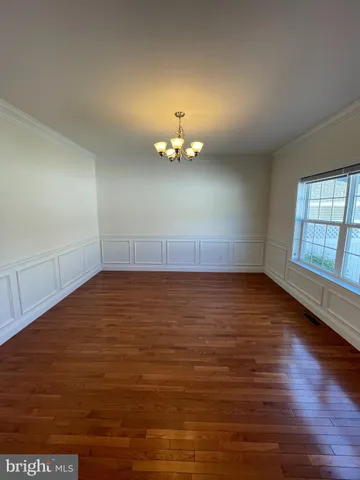 an empty room with wooden floor chandelier fan and windows