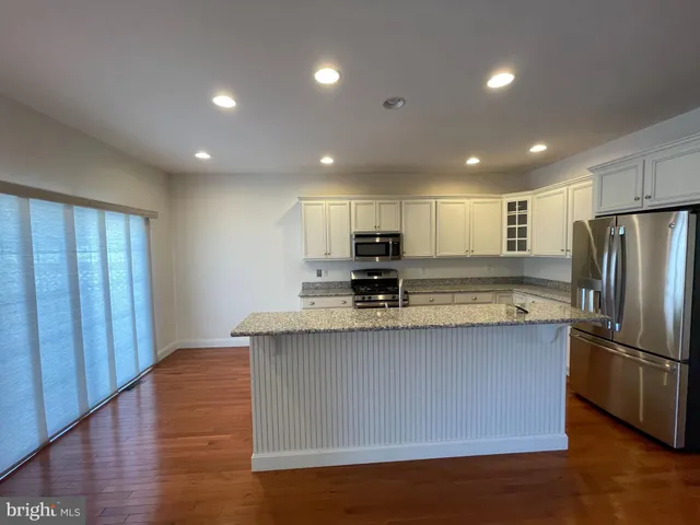 a view of kitchen with stainless steel appliances granite countertop a stove a refrigerator a sink and a refrigerator with wooden floor
