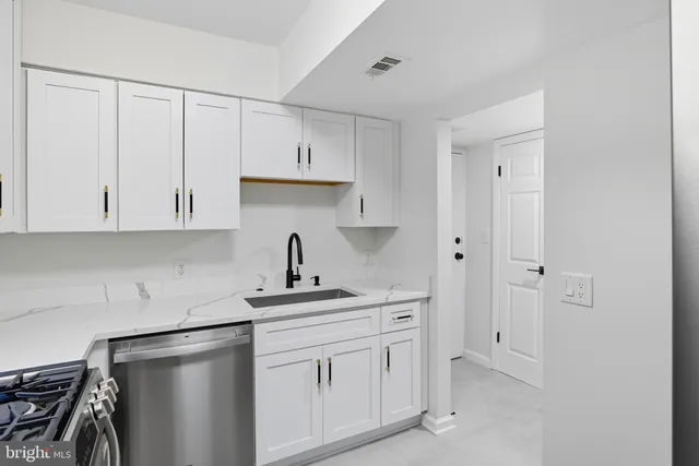 a kitchen with white cabinets and sink