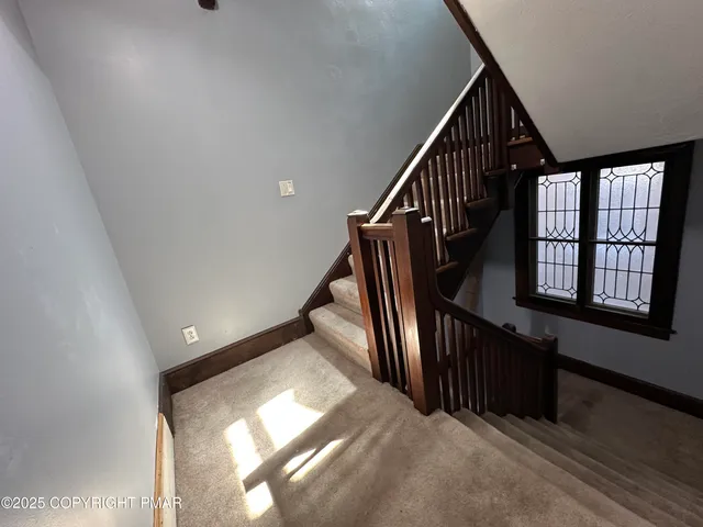 a view of staircase with lots of frames on wall and windows