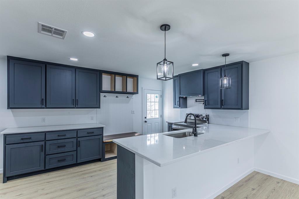 1026 La Clede Street Bellmead, TX 76705 - Photo 6 of 27 a kitchen with a sink center island cabinets and wooden floor