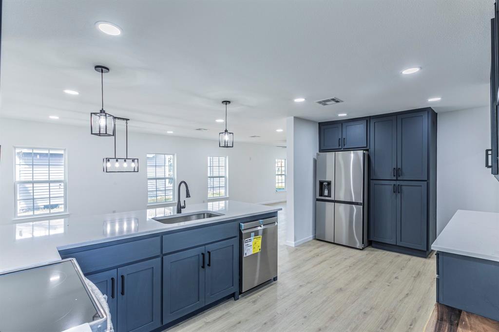 1026 La Clede Street Bellmead, TX 76705 - Photo 7 of 27 a kitchen with stainless steel appliances kitchen island granite countertop a refrigerator a sink dishwasher a oven and a large island with wooden floor