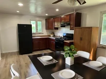 a kitchen with stainless steel appliances kitchen island granite countertop a refrigerator a stove a sink dishwasher and a dining table with wooden floor