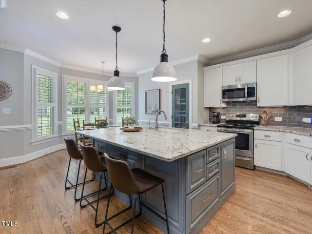 a kitchen with stainless steel appliances granite countertop white cabinets stove top oven and sink