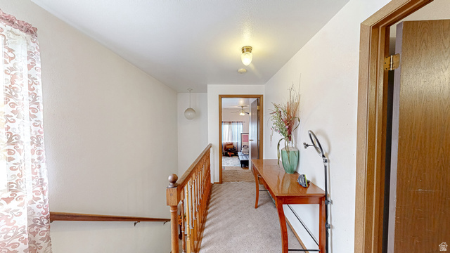 630 1100 West Provo, UT 84601 - Photo 48 of 64 Carpeted hallway featuring a wooden banister, overhead lighting, and wood-finish doors