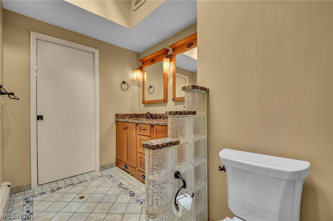 6845 Liberty Road Solon, OH 44139 - Photo 28 of 47 Bathroom vanity featuring a granite-style countertop, wood-finish cabinetry, and dual wall-mounted sconces