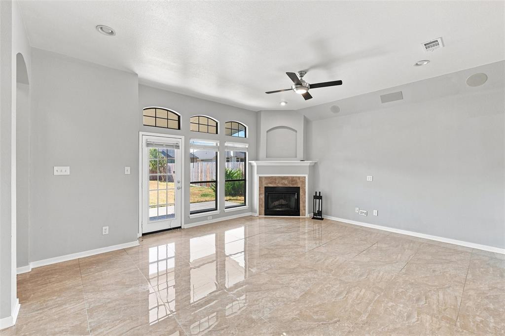 10409 Condor Loop Waco, TX 76708 - Photo 13 of 26 Spacious room featuring large format tile flooring, a corner fireplace with a mantel, a ceiling fan, and multiple windows with arched transoms